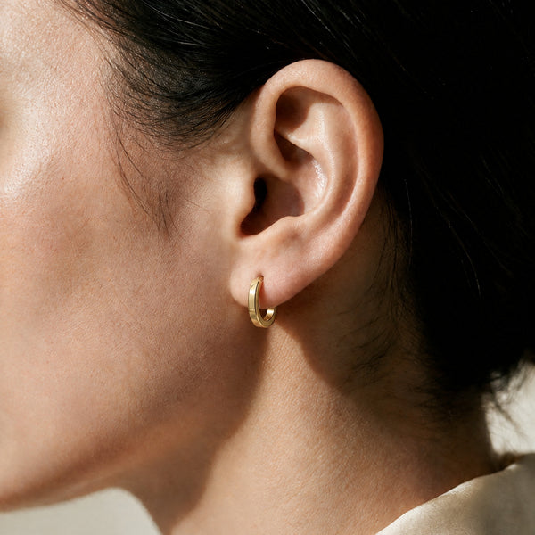 Daylight Huggies worn on the ear, a small 16mm gold hoop sitting close against the earlobe
