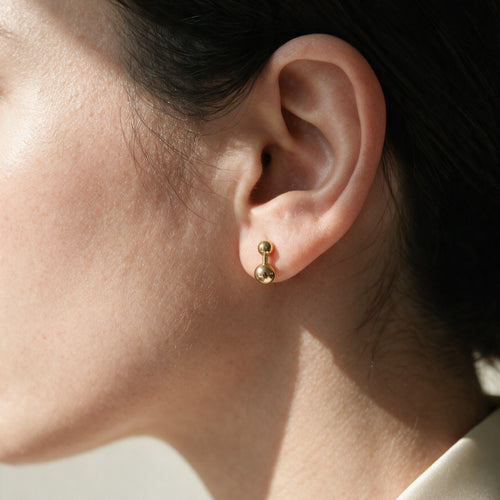 Echo Studs worn on the ear, a small 10mm gold barbell stud sitting within the earlobe