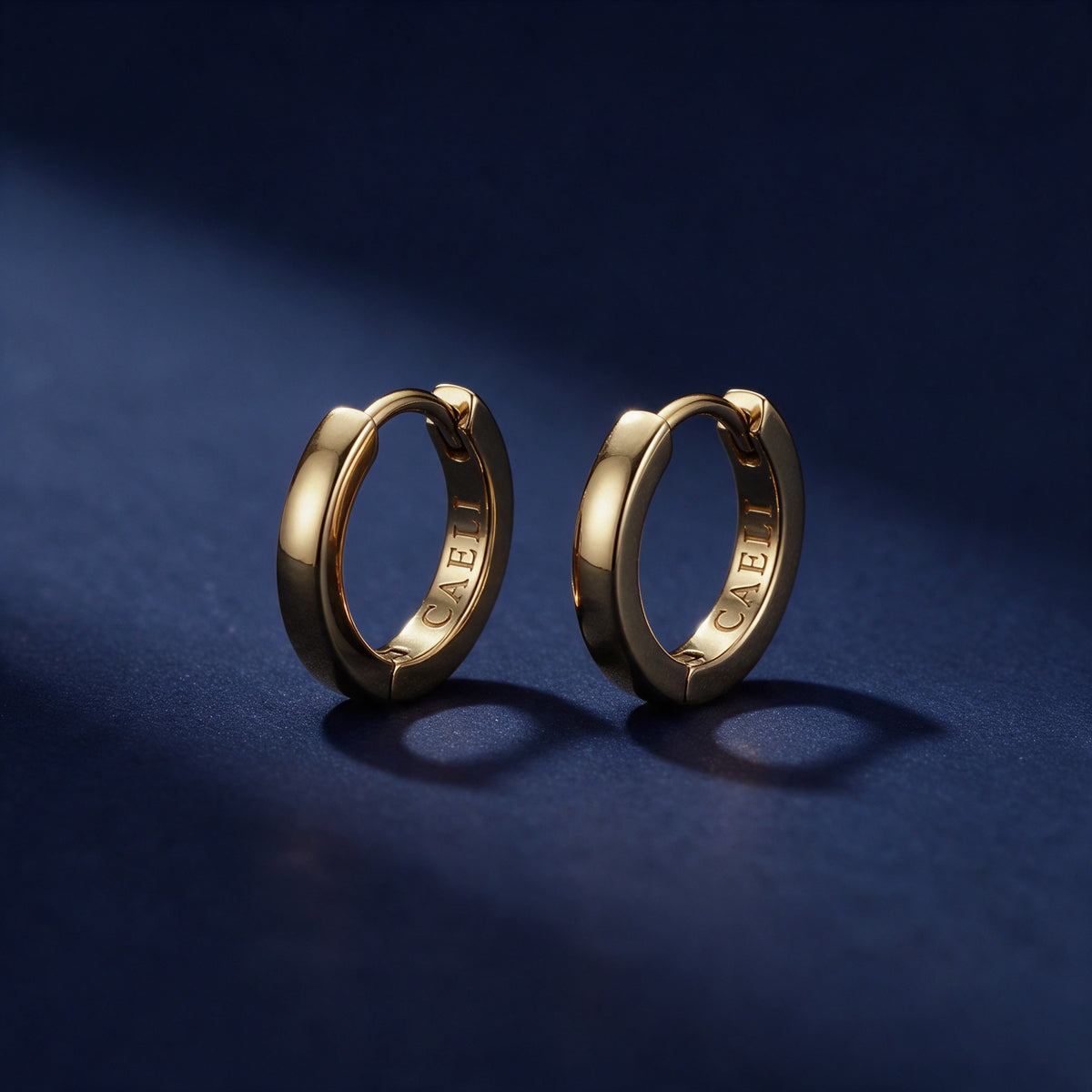 Daylight Huggies, a pair of 16mm gold huggie hoops on deep navy